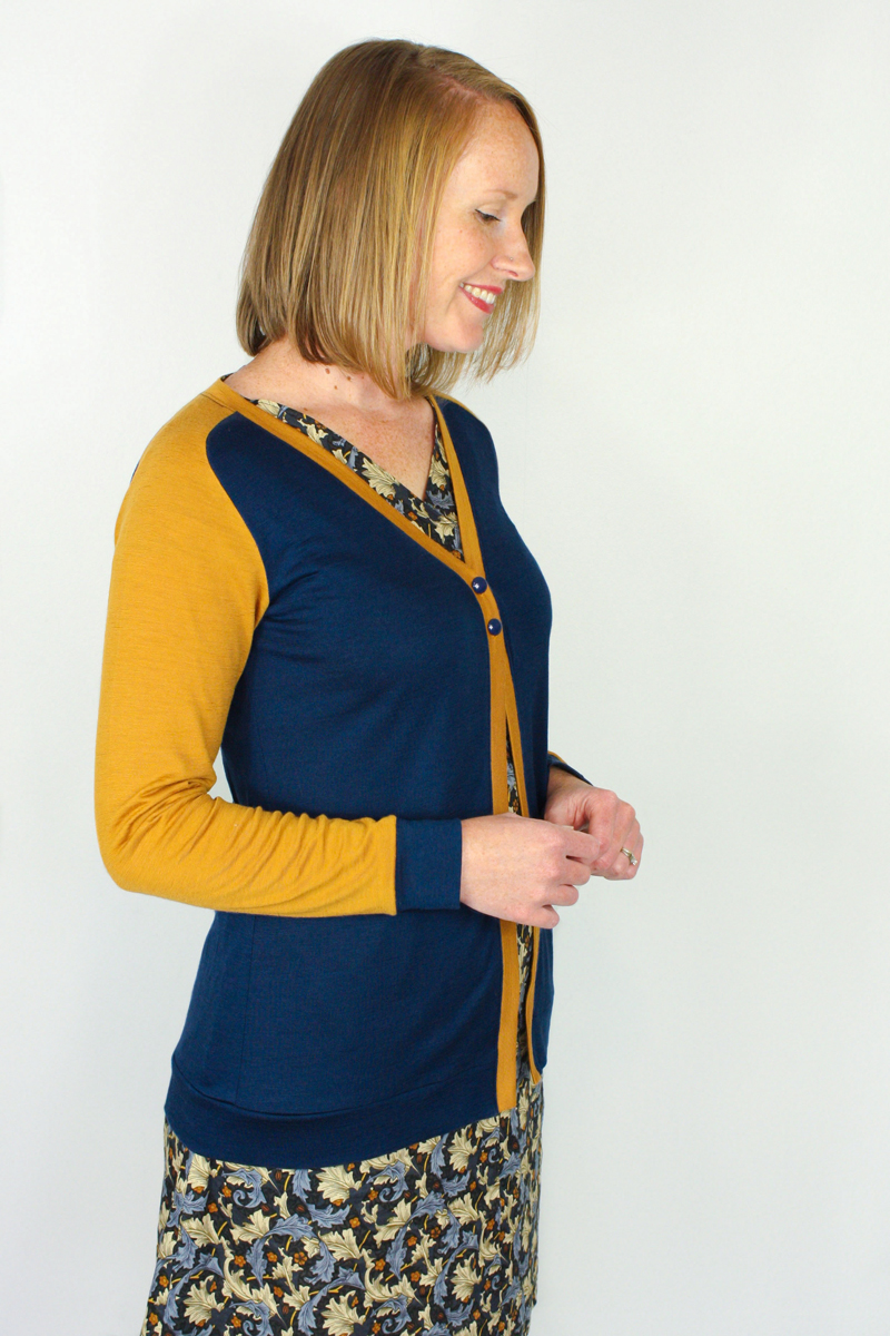 model wears a bright yellow and blue, colour-blocked cardigan that closes at the front and extends to hip level